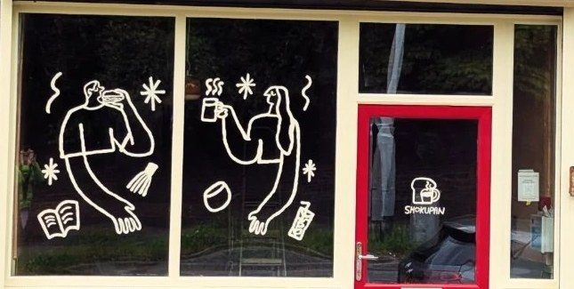 Hand-drawn figures with coffee, a book and a whisk painted on the SHOKUPAN windows